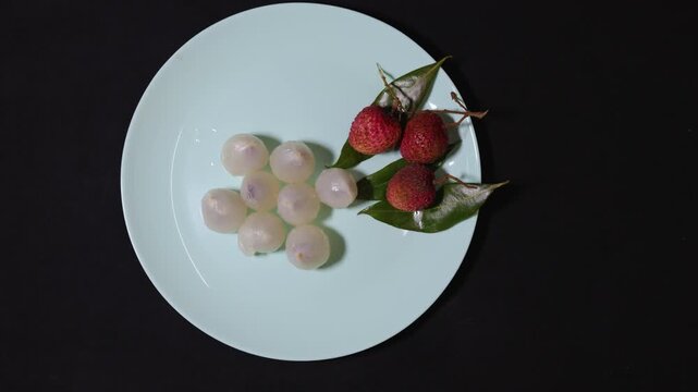 fresh peeled lychee pulp and whole lychees on elegant white serving plate