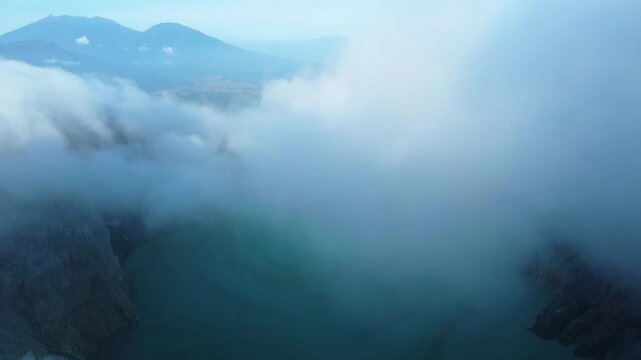 Aerial view of ijen volcano crater lake flying through clouds