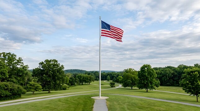 American flag waving on a tall pole in a green park setting