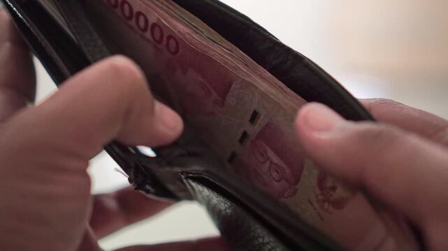 Hands counting banknotes from a wallet during a payment or purchase. Suitable for business, budgeting, finance, savings, and money management concepts.