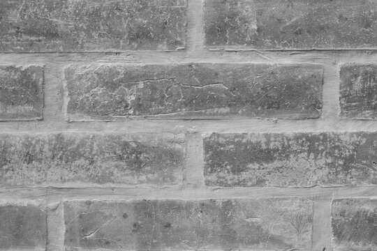 Black and white close-up texture of an old weathered brick wall with visible cement lines, perfect for rustic and grunge background designs.