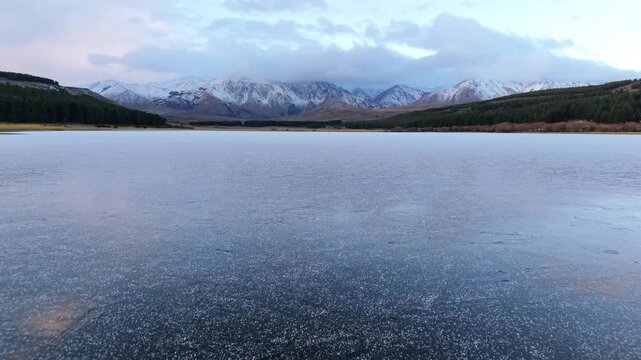 Frozen Laguna La Zeta with snow covered mountains near Esquel Chubut, drone aerial establishing