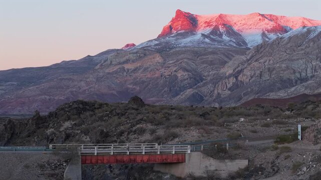 Volcanic canyon landscape in La Payunia Provincial Reserve near Pay&uacute;n Matr&uacute; volcano, Mendoza, Argentina, with eroded lava terrain, rugged Andean foothills and bridge at sunrise light, drone sliding