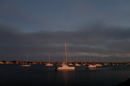 Sunset light makes the white sailboats and catamarans glow in St. Augustine Florida waterway during a winter sunset