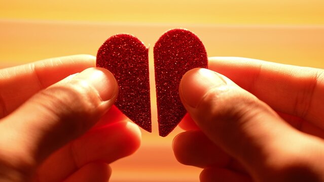 Two hands gently bring together the two halves of a red heart under warm sunlight, representing reconciliation, forgiveness, healing, hope, and the power of renewed connection after separation.
