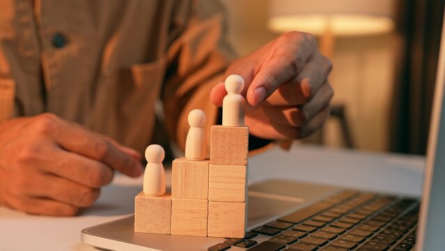 A strategist places a male wooden figure at the top while female figures remain lower, symbolizing workplace inequality, the gender gap in career advancement, challenges in organizational diversity.

