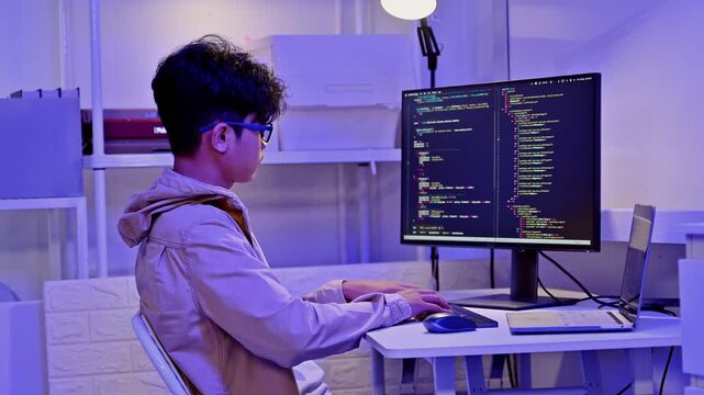 Focused IT Specialist Write Code On Dual Monitor Setup In Neon Workspace