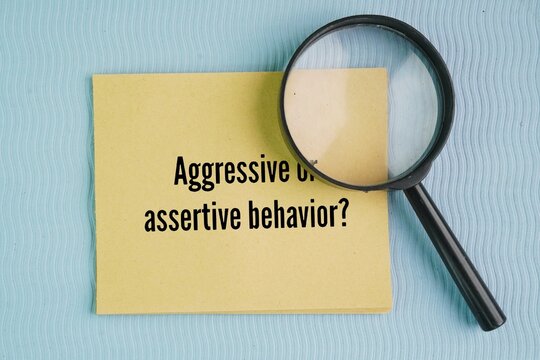 Magnifying glass and paper with the words aggressive or assertive behavior? standing up for your rights and expressing your needs clearly, honestly, and respectfully