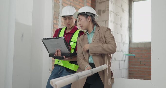 Male site engineer and female architect compare printed blueprints with a digital plan at a residential construction site, checking design details against real site work.
