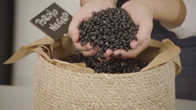 Poroto negro seco, legumbre para alimentaci&oacute;n saludable y prote&iacute;na vegetal, mano sosteniendo y dejando caer granos en c&aacute;mara lenta (Slow Motion), Footage cocina, comida