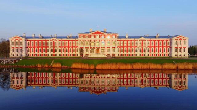 Baroque palace mirrored in still river beside golden reeds in Latvia
