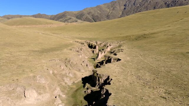 Eroded ravine landscape in Quebrada del Portugu&eacute;s near Taf&iacute; del Valle, Valles Calchaqu&iacute;es, Tucum&aacute;n, Argentina, featuring semi arid highland terrain and exposed geological formations, forward flyover