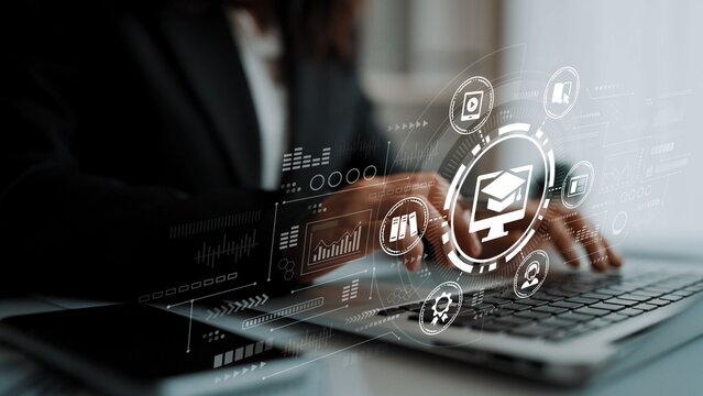 Professional Business Woman Using Laptop with Educational Icons and Digital Graphics Indicating E-Learning and Online Courses in Modern Office Environment. Entropy.