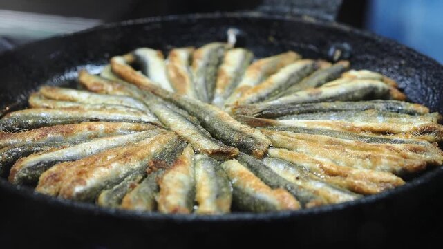 Cooking small fish in a frying pan at a local kitchen