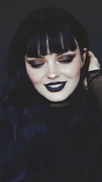 Young woman with dark hair and black lipstick posing for portrait. Fashion girl with goth makeup style modeling for camera. Beauty concept and trendy styling. Vertical video