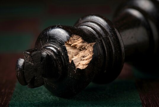 Extreme macro shot of snapped cross crown on black ebony wood chess king piece