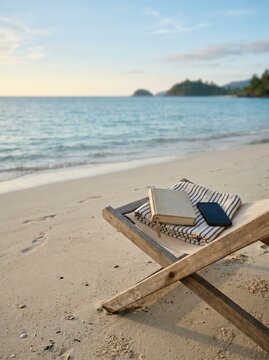 Comfortable beach chair, folded blanket, closed book, switched-off smartphone on private Andaman beach with calm ocean and soft morning sunlight