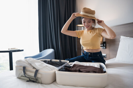 Young Hispanic American Gen Z Woman Packing Suitcase on Bed in Apartment for preparing for exciting travel adventure