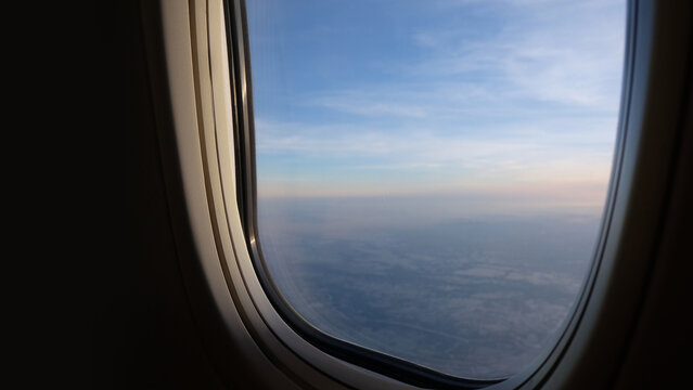 Beautiful sunset view from airplane window with wing above the clouds and golden sky