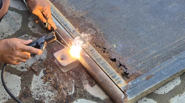 Worker Welding Metal Hinge Bracket on Heavily Rusted Iron Gate Frame Using Stick Welder