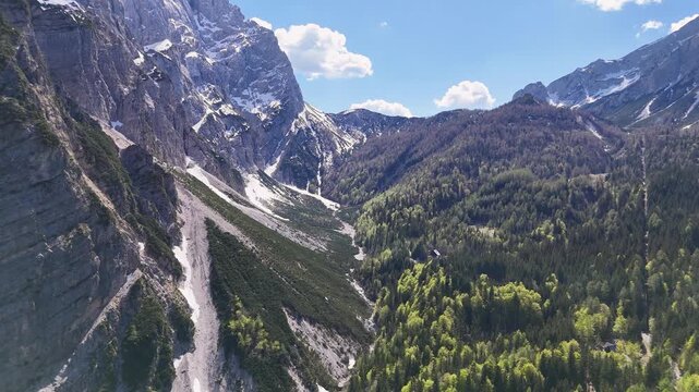 Jagged limestone peaks and green forested slopes rise above Tarvisio village in the Julian Alps of Friuli Venezia Giulia, Italy.