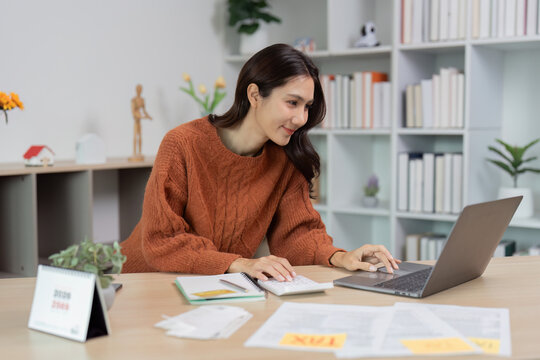 Woman working on a laptop and taking notes in a home office