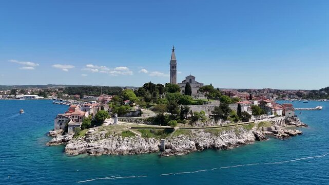 Elevated drone view of historic Rovinj, coastal houses, church tower, marina, islands, and the Adriatic Sea in Croatia.