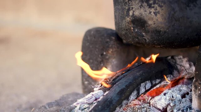 4K Closeup shot of wood burning in a traditional wood stove for preparation of food in rural India as seen in the villages of Gujarat, India. Food being prepared by burning wood in stove.