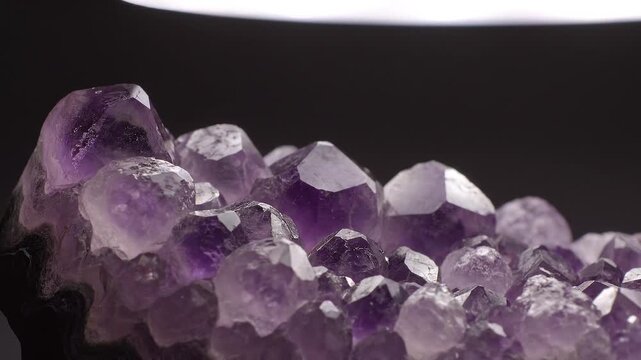 Captivating close-up of vibrant purple amethyst geode crystals, showcasing their natural beauty and intricate facets against a dark, reflective background
