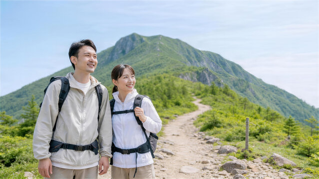 夏山の登山道を歩くカップルの山の日ハイキング
