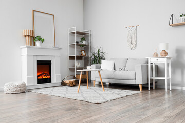 Obraz premium Cozy living room interior with modern gray sofa, electric fireplace, and stylish home decor elements
