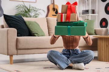 Fototapeta premium Young woman holding stack of wrapped holiday gifts, celebration and surprise, festive occasion, home interior