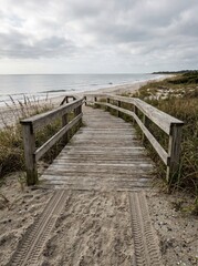 Fototapeta premium Empty accessible beach ramp with wheelchair tire marks in the sand, representing inclusive tourism, mobility access, and barrier-free travel.