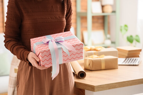 Woman holding a beautifully wrapped pink gift box with blue and pink ribbon, celebration and holiday present