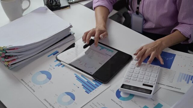 Businessperson Analyzing Financial Data Using Tablet and Documents at Desk