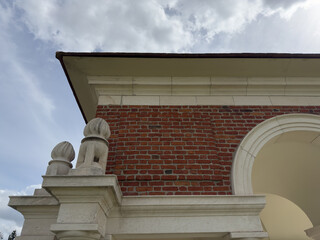 Red brick cemetery monument with white stone arch under cloudy sky © Florian Dussart