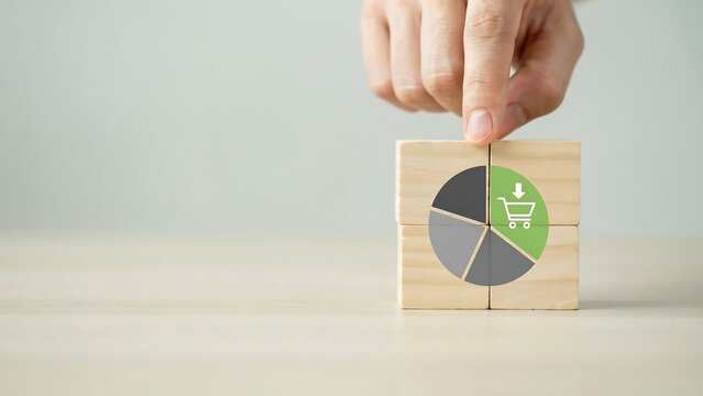 A hand placing a wooden block with a pie chart and shopping icon on a table