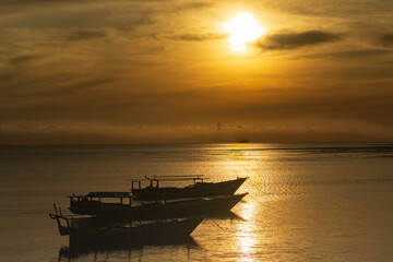 Obraz premium It's still early morning, the sun has just risen higher, a golden yellow color appears, no fishermen have gone out to sea yet, and a few wooden boats are still seen moored near the dock