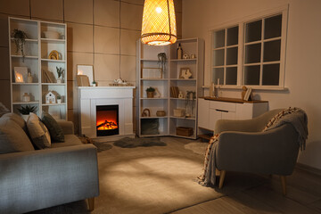 Obraz premium Cozy living room interior with electric fireplace, sofa, armchair, and bookshelves for home comfort