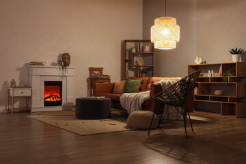 Obraz premium Cozy living room interior with electric fireplace, comfortable sofa, and warm lighting for relaxation