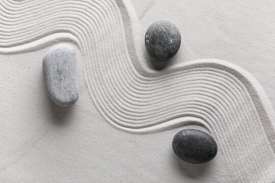 Zen garden raked sand with smooth gray stones, serenity and balance concept, mindfulness and meditation background