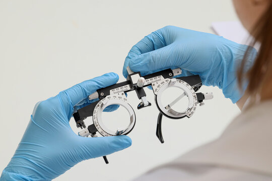 Optometrist hands in blue gloves adjusting phoropter for vision test and eye examination in clinic, precision and professional care involved in modern healthcare and optometry services