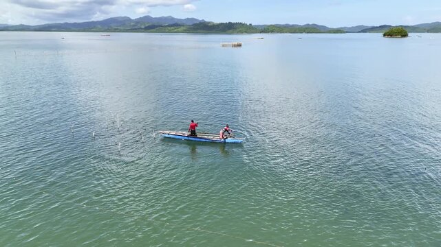 Tight orbit around fishermen casting a net into chlorophyll-rich waters of Inner Malampaya Sound. Water splashes visibly as the net hits the surface