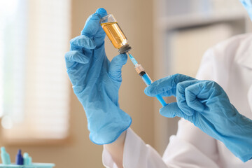 Medical professional in blue gloves preparing syringe with vaccine from vial for injection,...