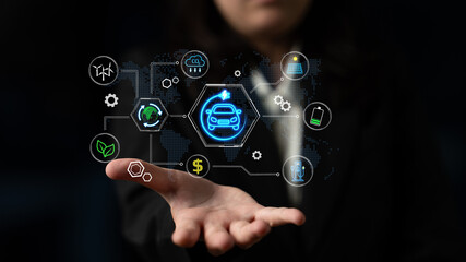 Fototapeta premium Business professional demonstrating innovative technology with holographic icons representing automotive, finance, environment, and data management elements in a dark setting. Entropy.