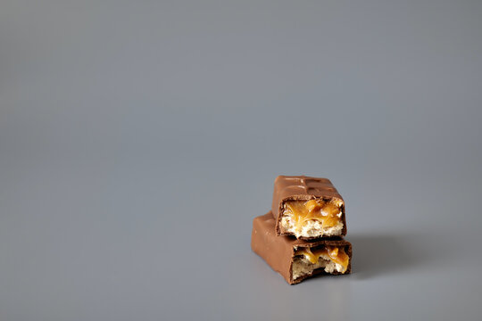 Two chocolate caramel candy bars isolated on a gray background, showcasing sweet confectionery products with a clean commercial presentation