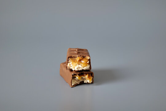 Two chocolate caramel candy bars isolated on a gray background, showcasing sweet confectionery products with a clean commercial presentation