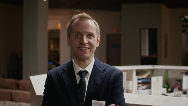 Portrait of middle aged Caucasian male hotel receptionist standing with arms crossed and smiling at camera. Clip is ideal for hospitality industry marketing and corporate hotel service videos