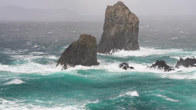 Rough waves crashing against rocky sea stacks in iceland
