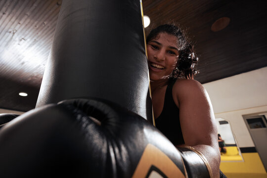 Young Woman Boxing With Punching Bag in Gym Smiling During Fitness Training Session